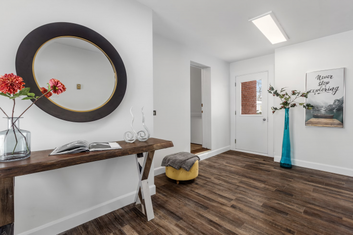 a modern decorated hallway with white walls, dark brown luxury vinyl tiles and colourful furniture.